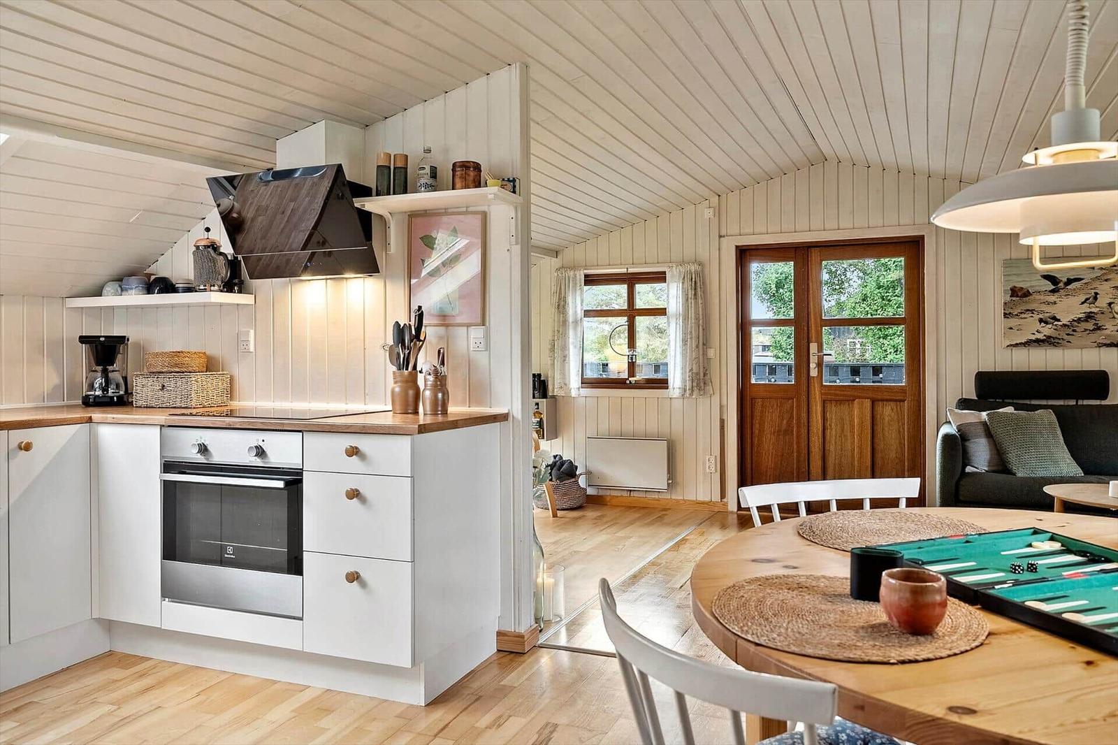Kitchen with dining area and view into living room with sofa and door.