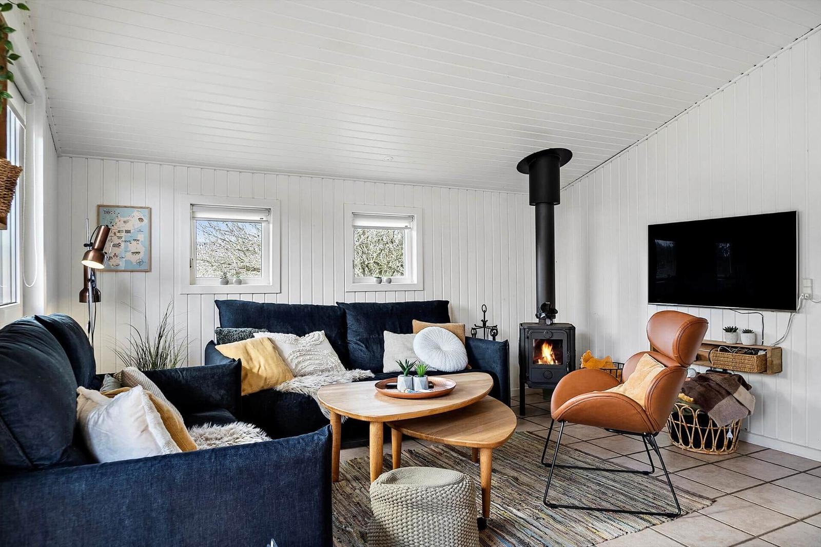 Wohnzimmer mit Sofa, Sessel, Kamin und Fernseher an weißer Wand.