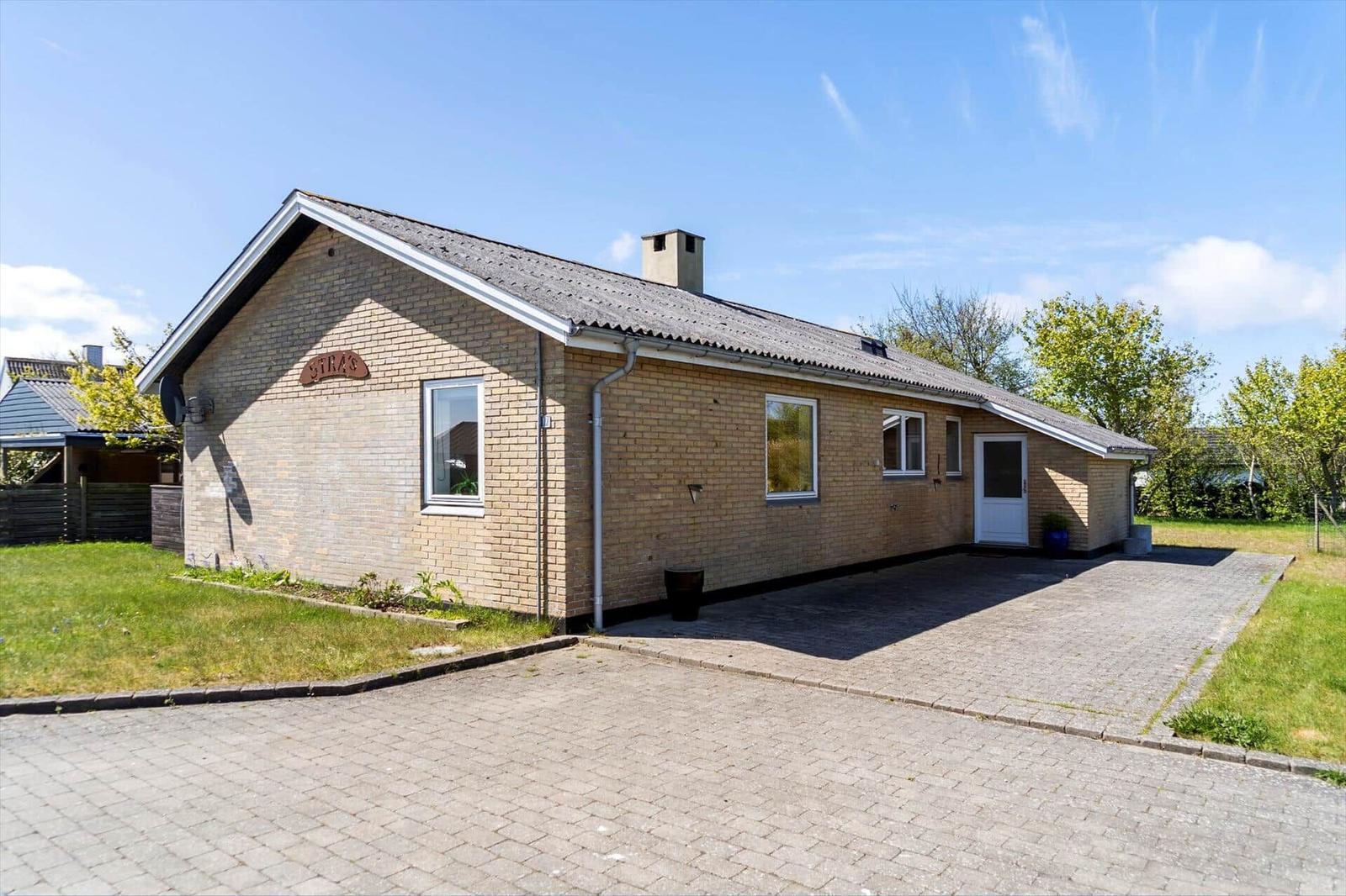 Einzelgeschossiges Haus mit Backsteinfassade und Kiesweg. Hinterhof mit Grünfläche.