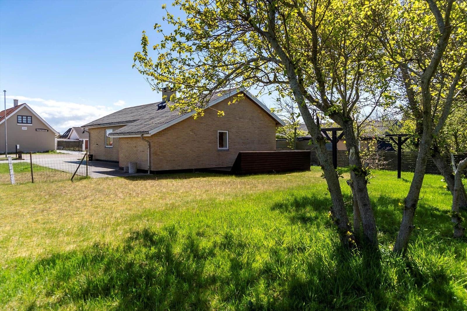 Ein Haus mit Garten und Bäumen unter blauem Himmel.