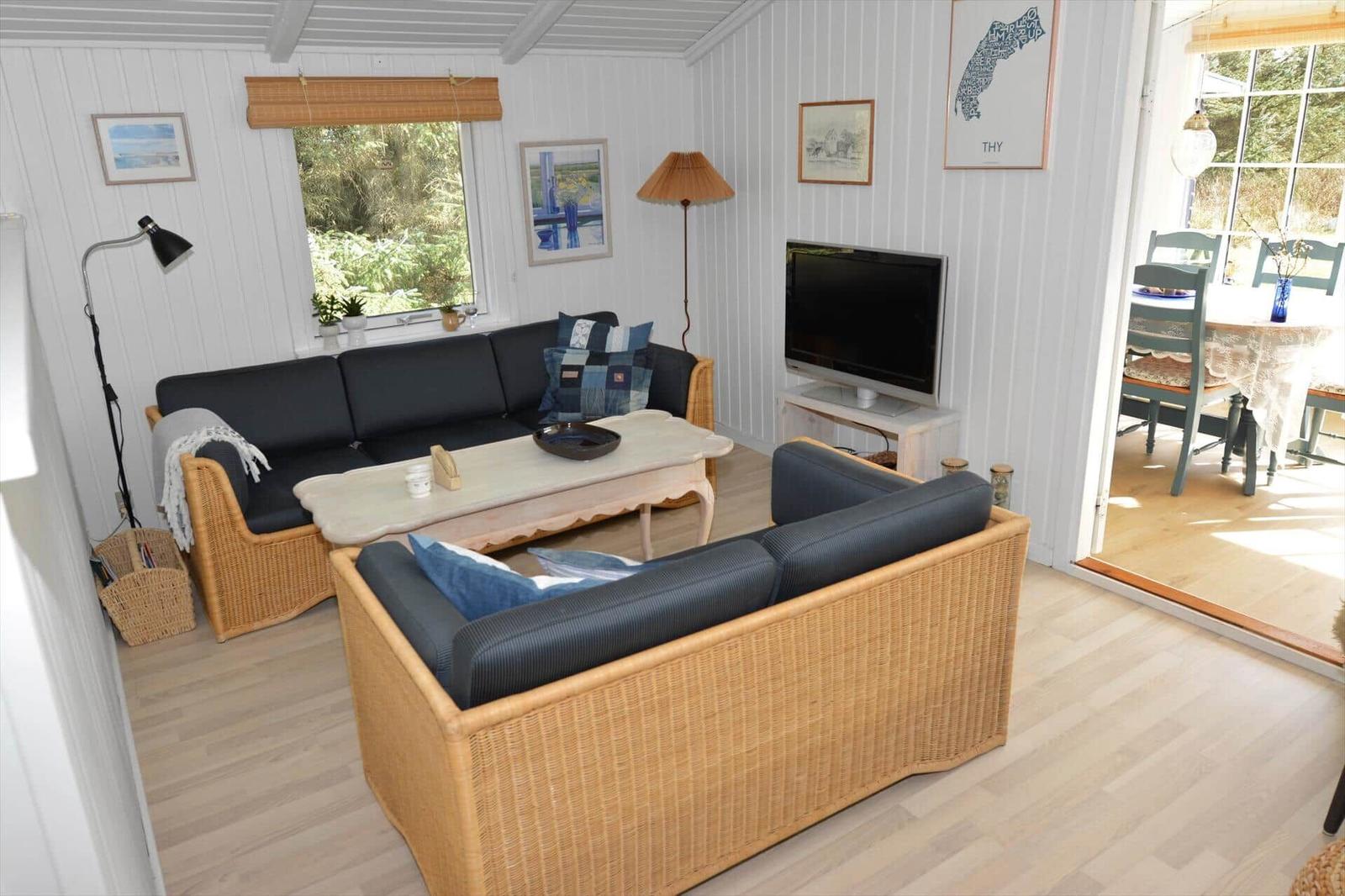 Wohnzimmer mit zwei Sitzgruppen, Fernseher und Blick auf Essbereich.