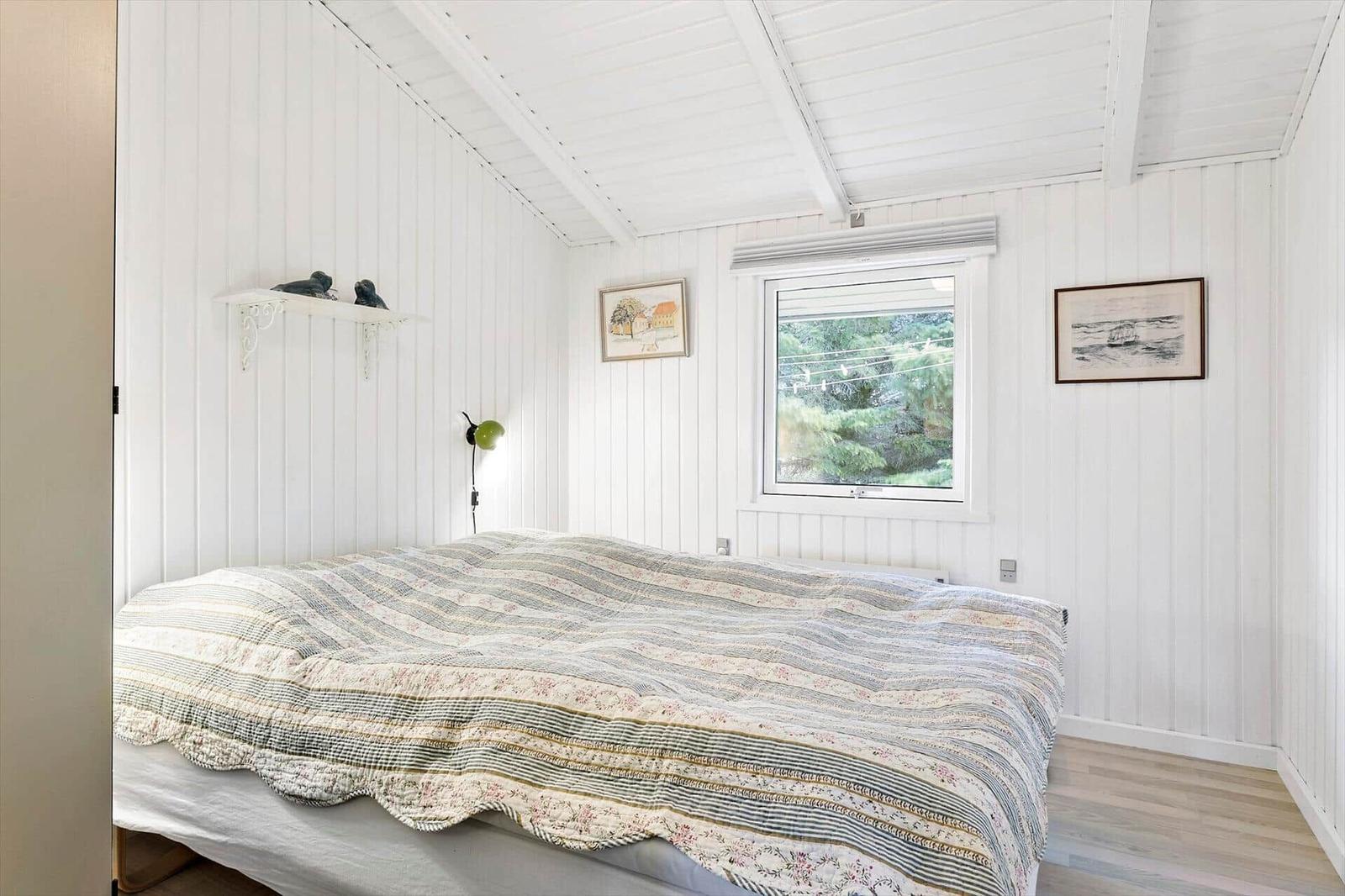 Schlafzimmer mit Bett, Fenster und Wanddekoration.