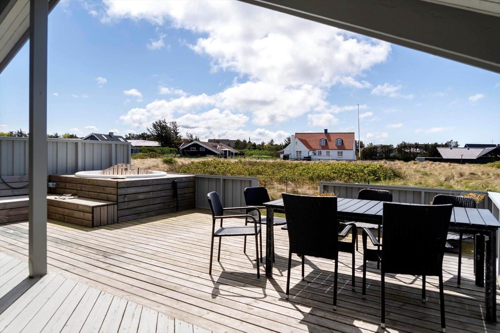 Terrasse mit Sitzgruppe und Whirlpool. Blick auf ländliche Umgebung mit Häusern.