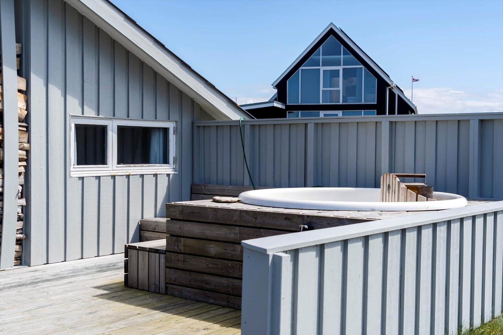Außenbereich mit Whirlpool, Holzterrasse und angrenzenden Häusern.