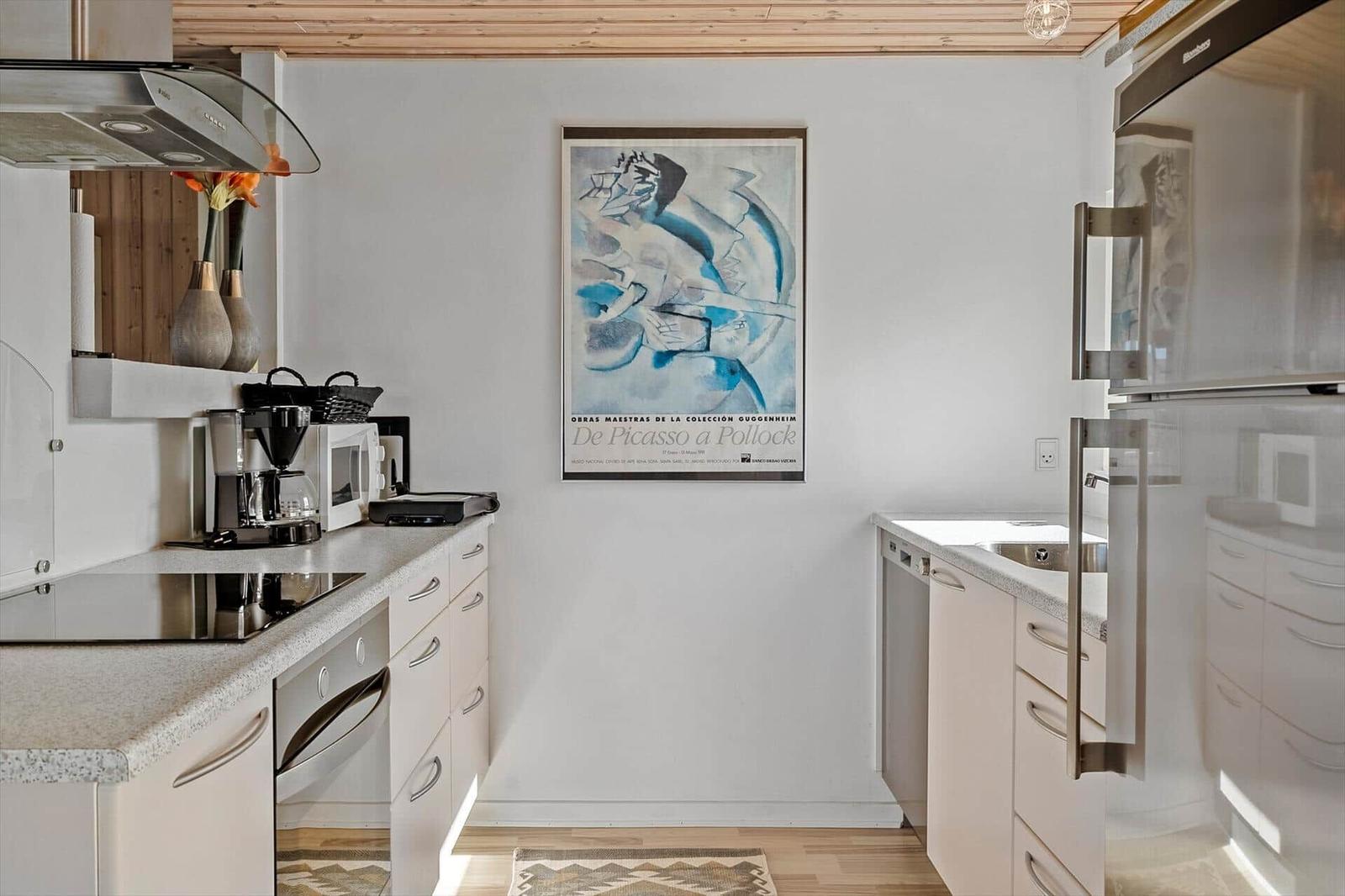 Küche mit weißen Schränken, Edelstahlgeräten und einem Kunstwerk an der Wand.