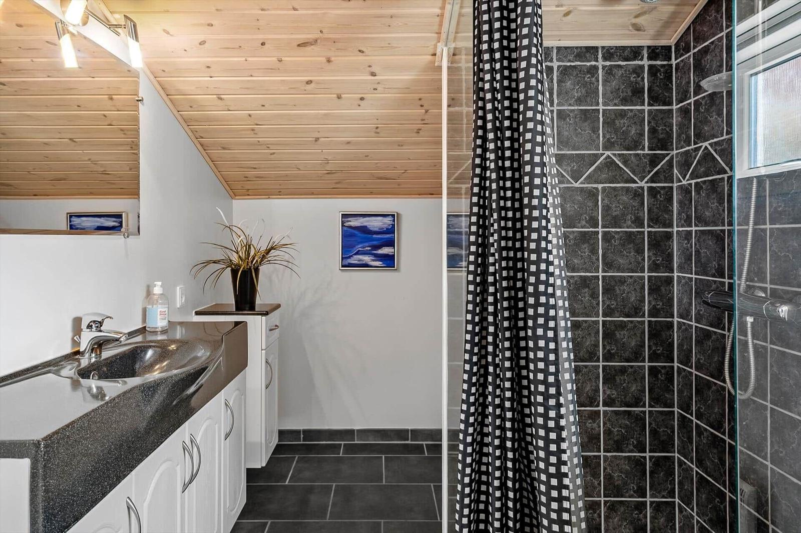 Badezimmer mit Dusche, Waschbecken und Holzdecke.