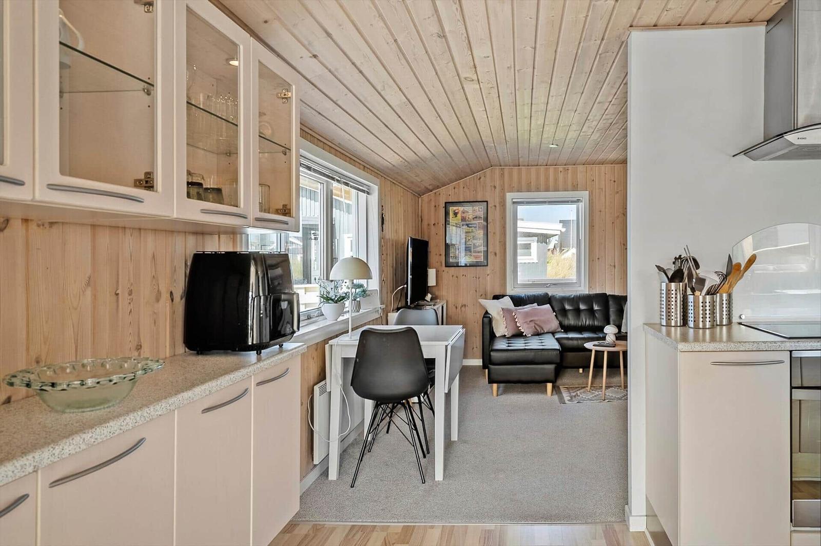 Küche mit Essbereich und Wohnzimmer mit Ledersofa und Holzwand