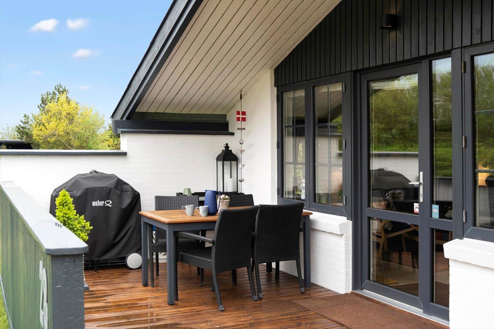Terrasse mit Tisch, Stühlen und Grill unter Dach
