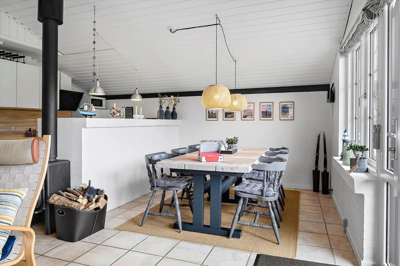 Essbereich mit Tisch, Stühlen und Fenster. Hängelampen, Bilder und Kamin.