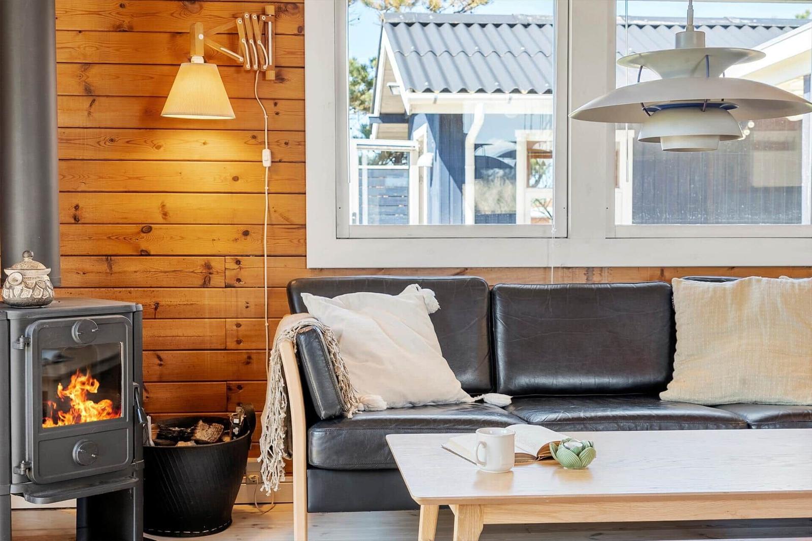 Ein Wohnzimmer mit einem Sofa, einem Kaminofen und einem Fenster.