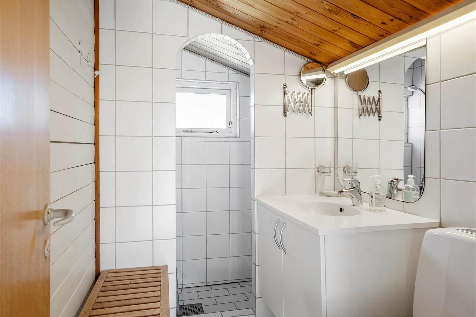 Badezimmer mit Dusche, Waschbecken und Spiegel
