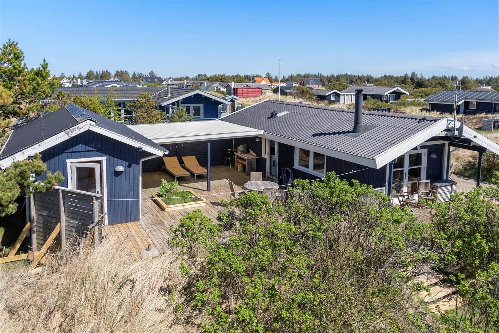 Blau gestrichenes Haus mit Terrasse und Garten. Blick auf die Umgebung.