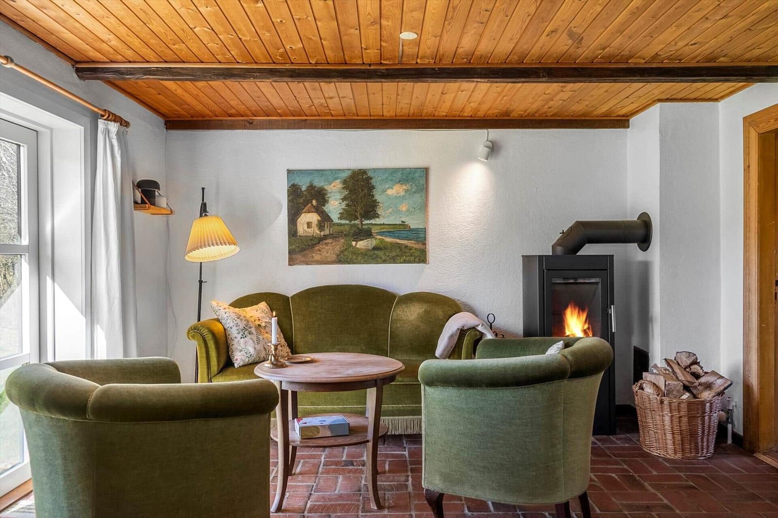 Living room with green chairs, fireplace, and wooden ceiling.