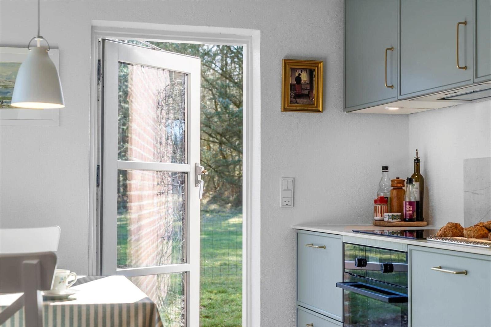 Kitchen with garden view, light blue cabinets, and countertop with oven.