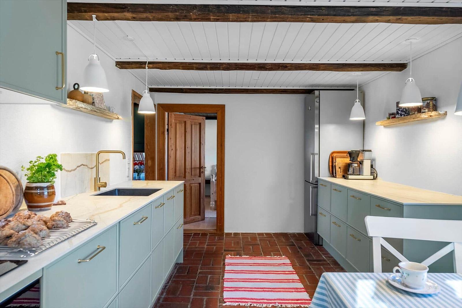 Kitchen with light cabinets, red floor, and wooden beams on the ceiling.