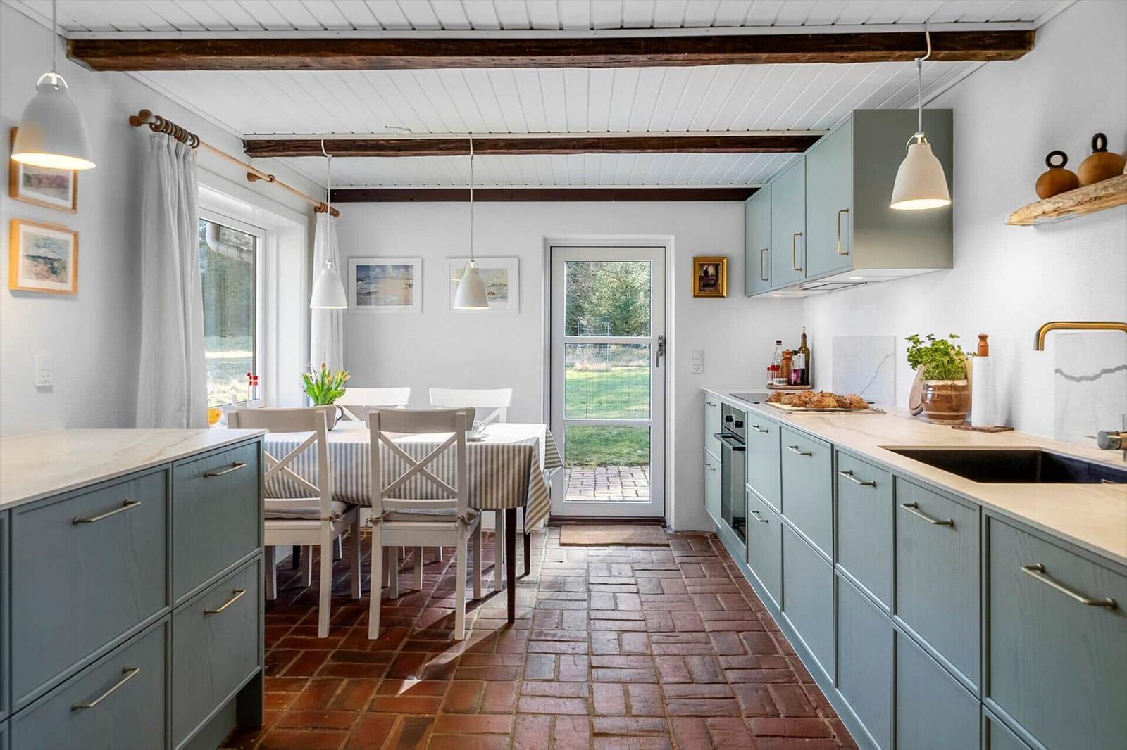 Kitchen and dining area with wooden floor, light cabinets, and window to the garden.