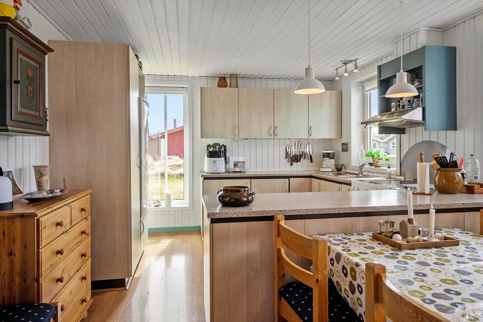 Kitchen with wooden furniture, countertop, and window view of outdoor area.