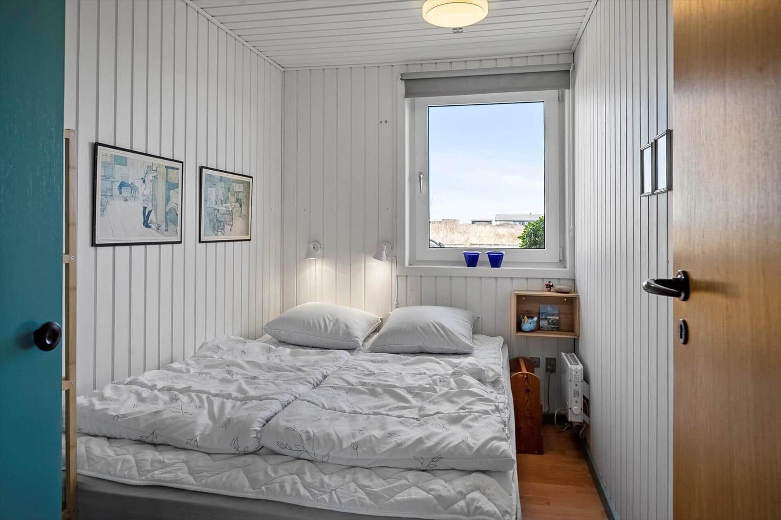 Bedroom with bed, window, and wall pictures.