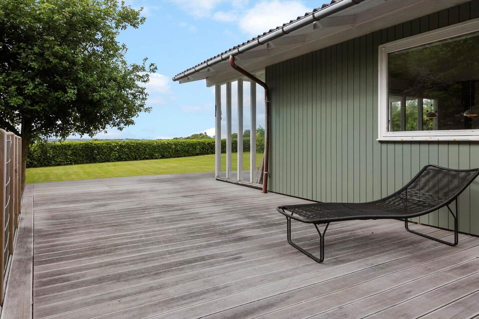 Terrasse mit Liegestuhl, Blick auf Rasen und Hecke