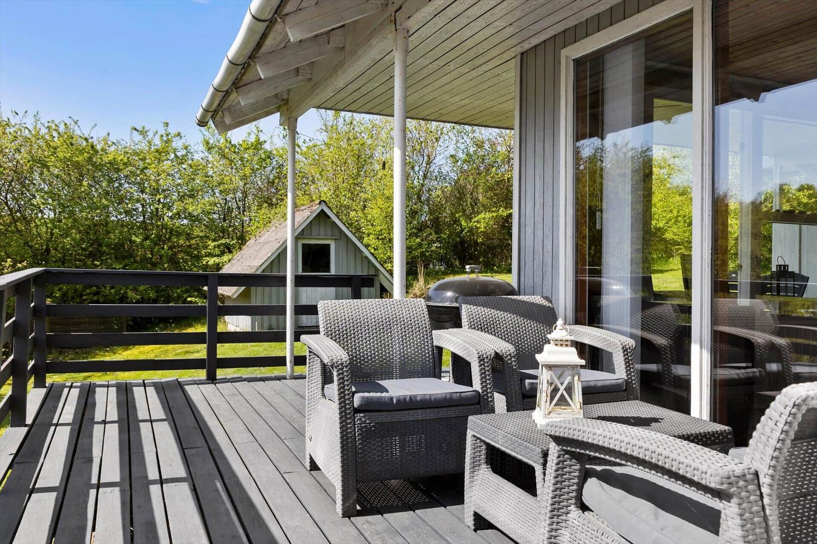 Terrasse mit Gartenmöbeln, Grill und Blick auf einen kleinen Garten.