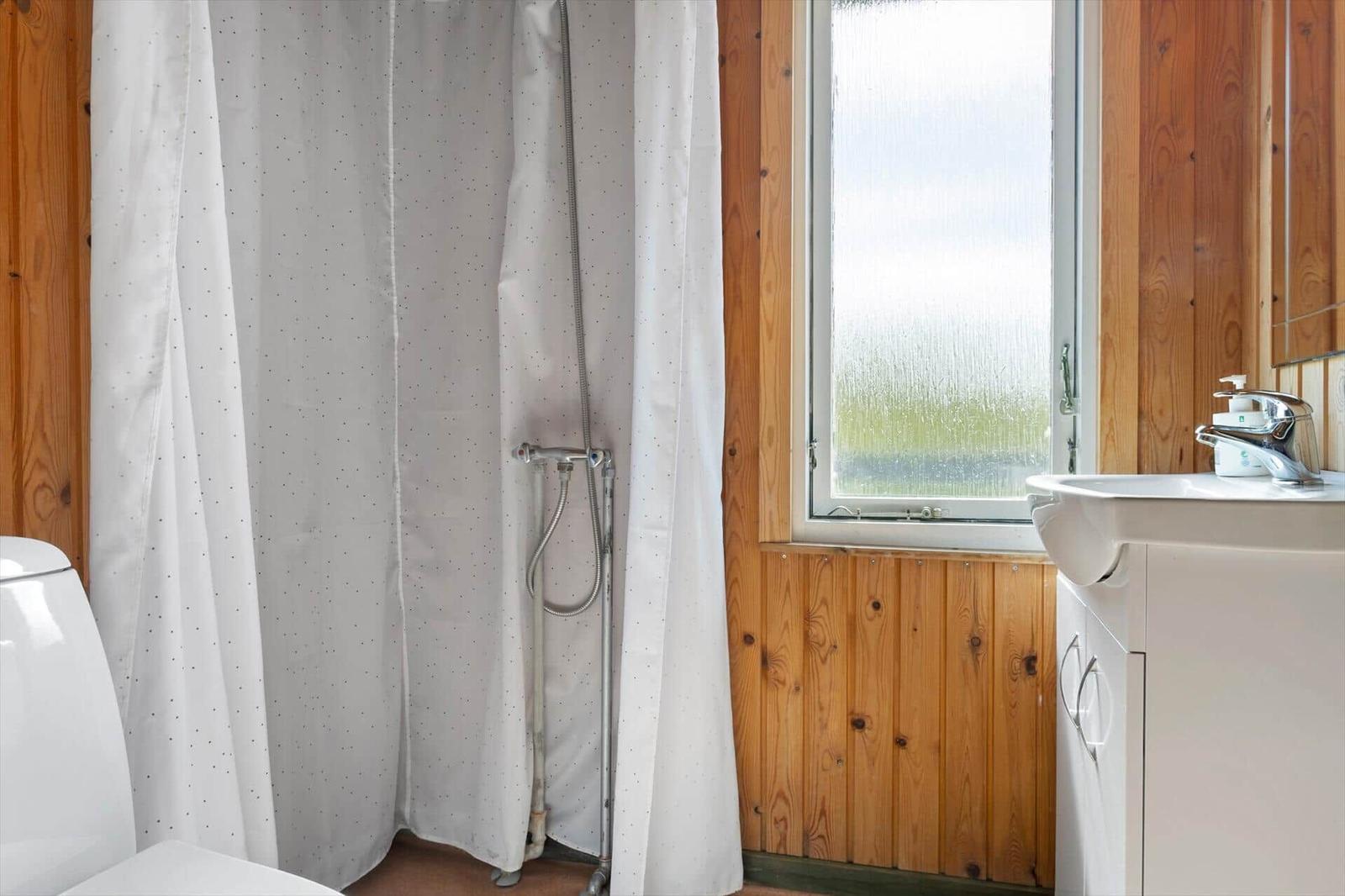 Badezimmer mit Dusche, Waschbecken und Fenster