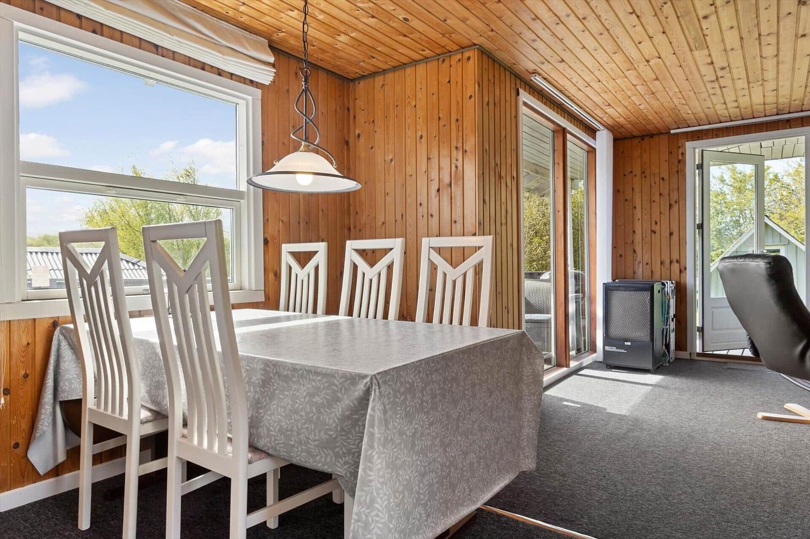 Esszimmer mit Tisch, Stühlen und Blick auf Außenbereich.