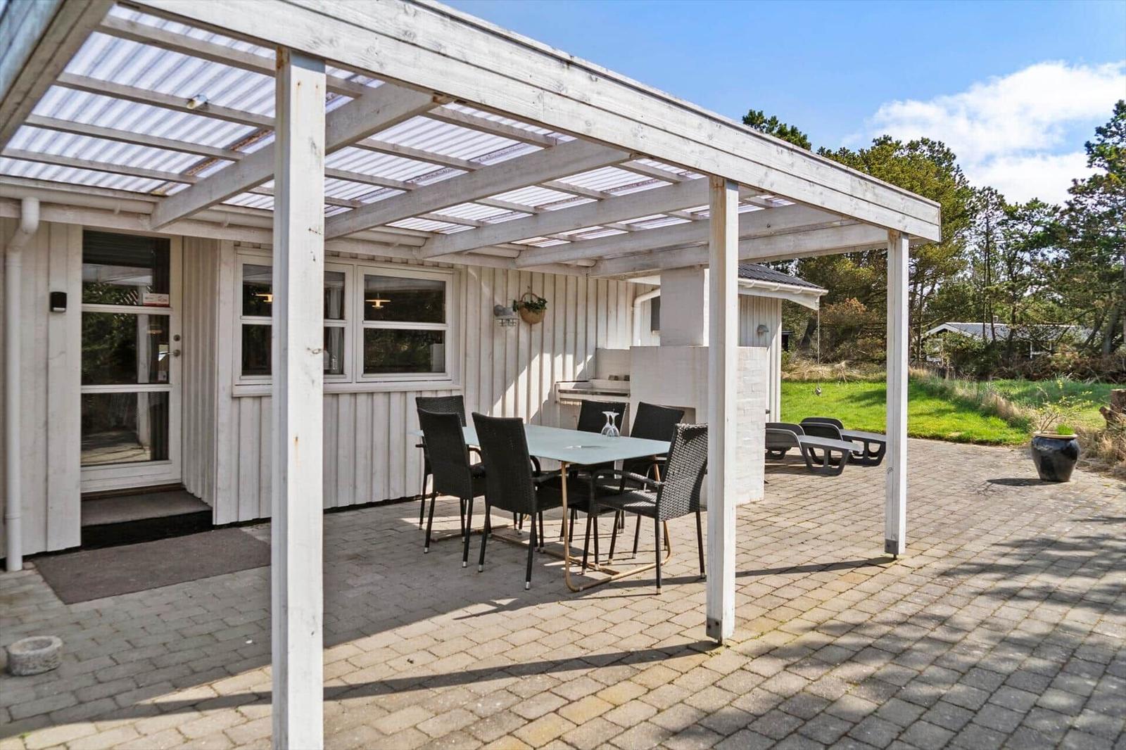 Terrasse mit Sitzgruppe unter Dach, Grill und Gartenbereich