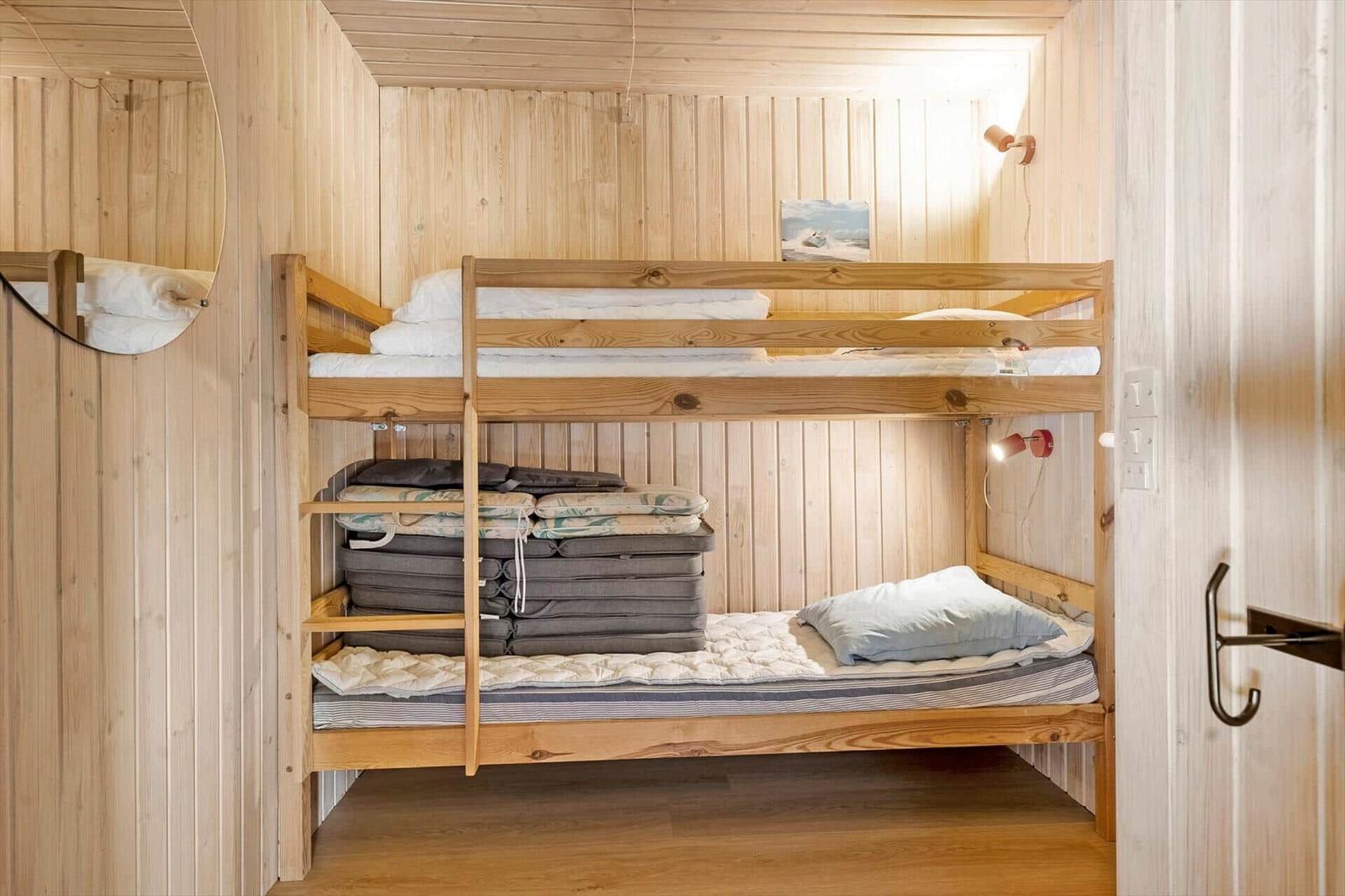 Holzbett mit zwei Schlafplätzen und Wandlampe