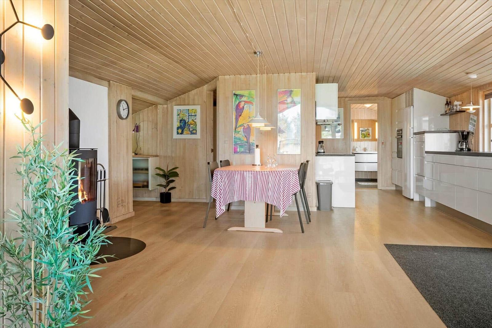 Moderne Küche und Essbereich mit Holzboden und -decke. Esstisch mit gestreifter Tischdecke.