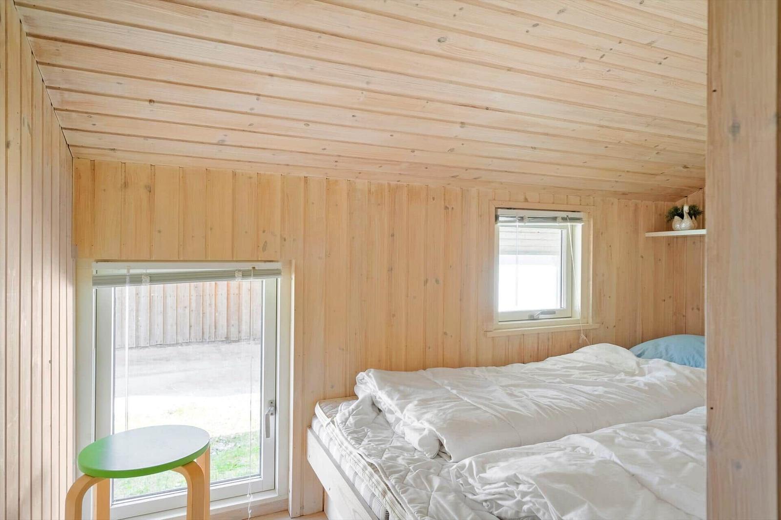 Ein Schlafzimmer mit Holzwänden, einem Bett und einem Fenster.