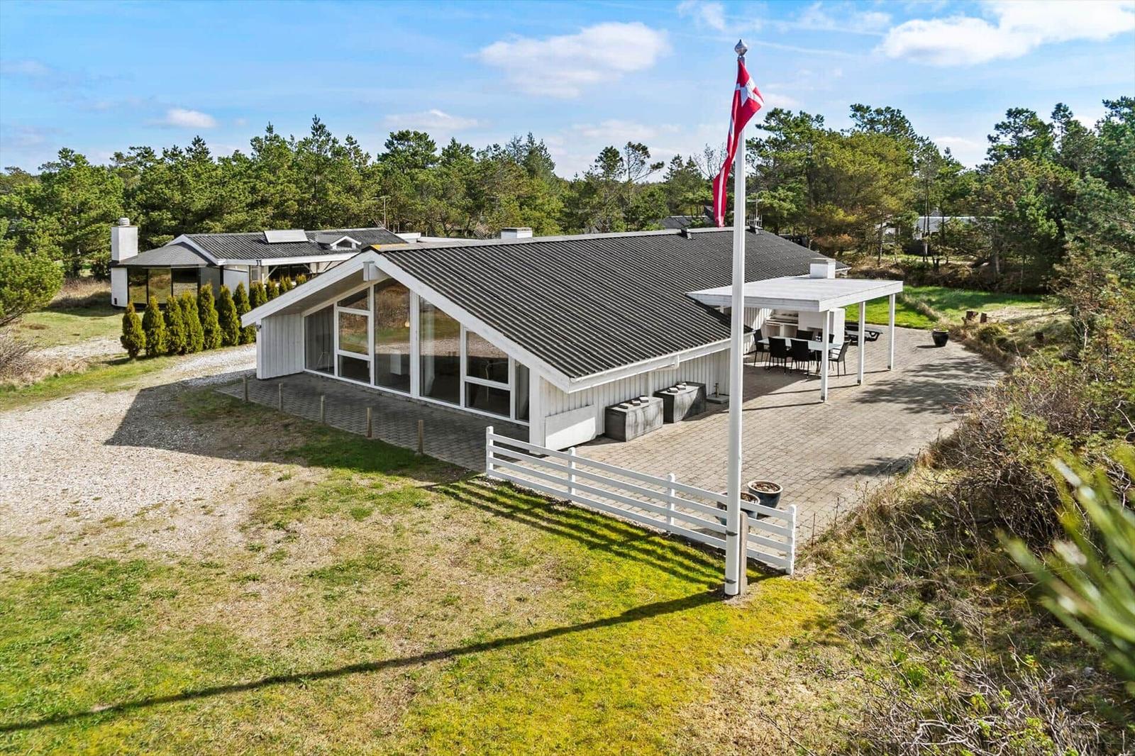 Moderne Villa mit Terrasse, Flagge und umliegenden Bäumen.
