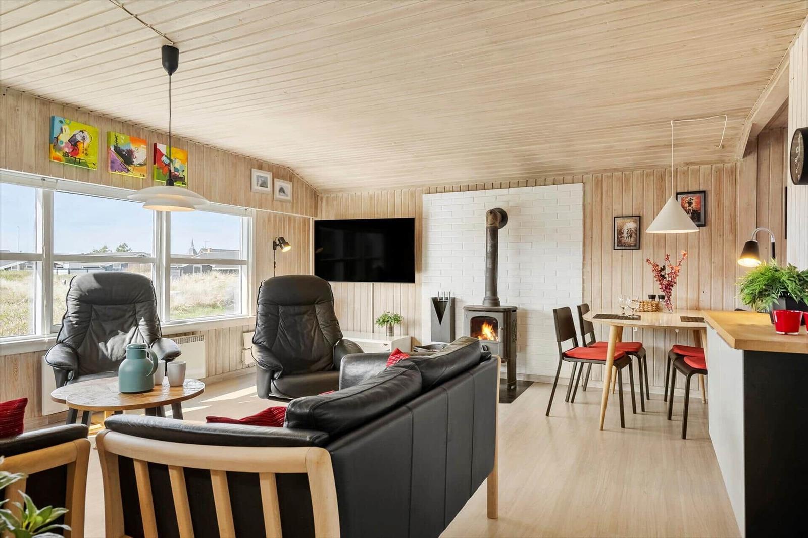 Living area with sofa, recliners, and fireplace. Dining table with chairs and windows.