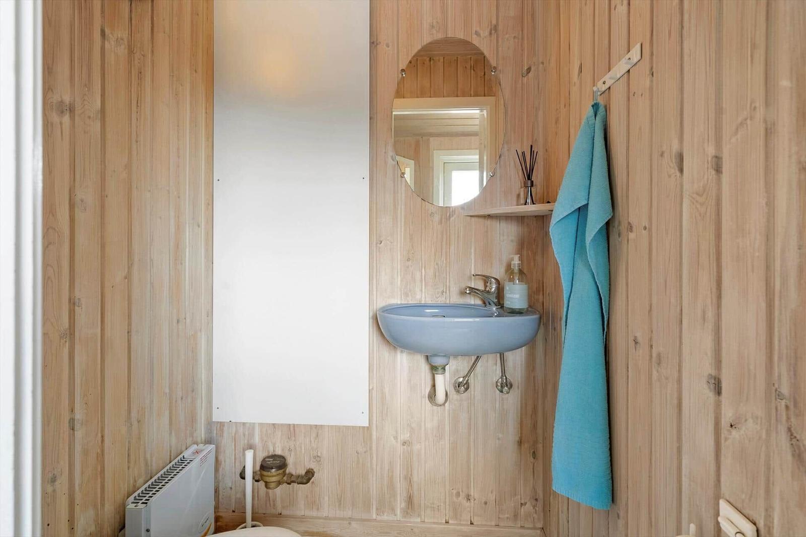 Bathroom with wooden walls, blue sink, and mirror