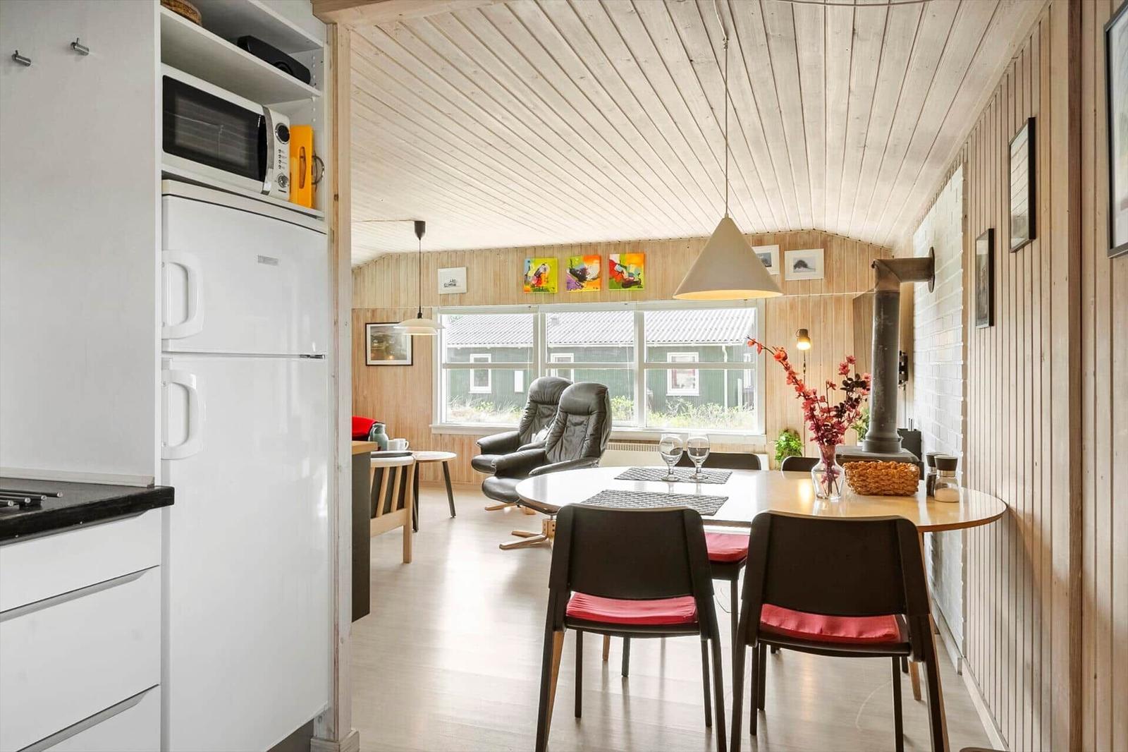 Kitchen with refrigerator and microwave. Dining area with table, chairs, and stove.