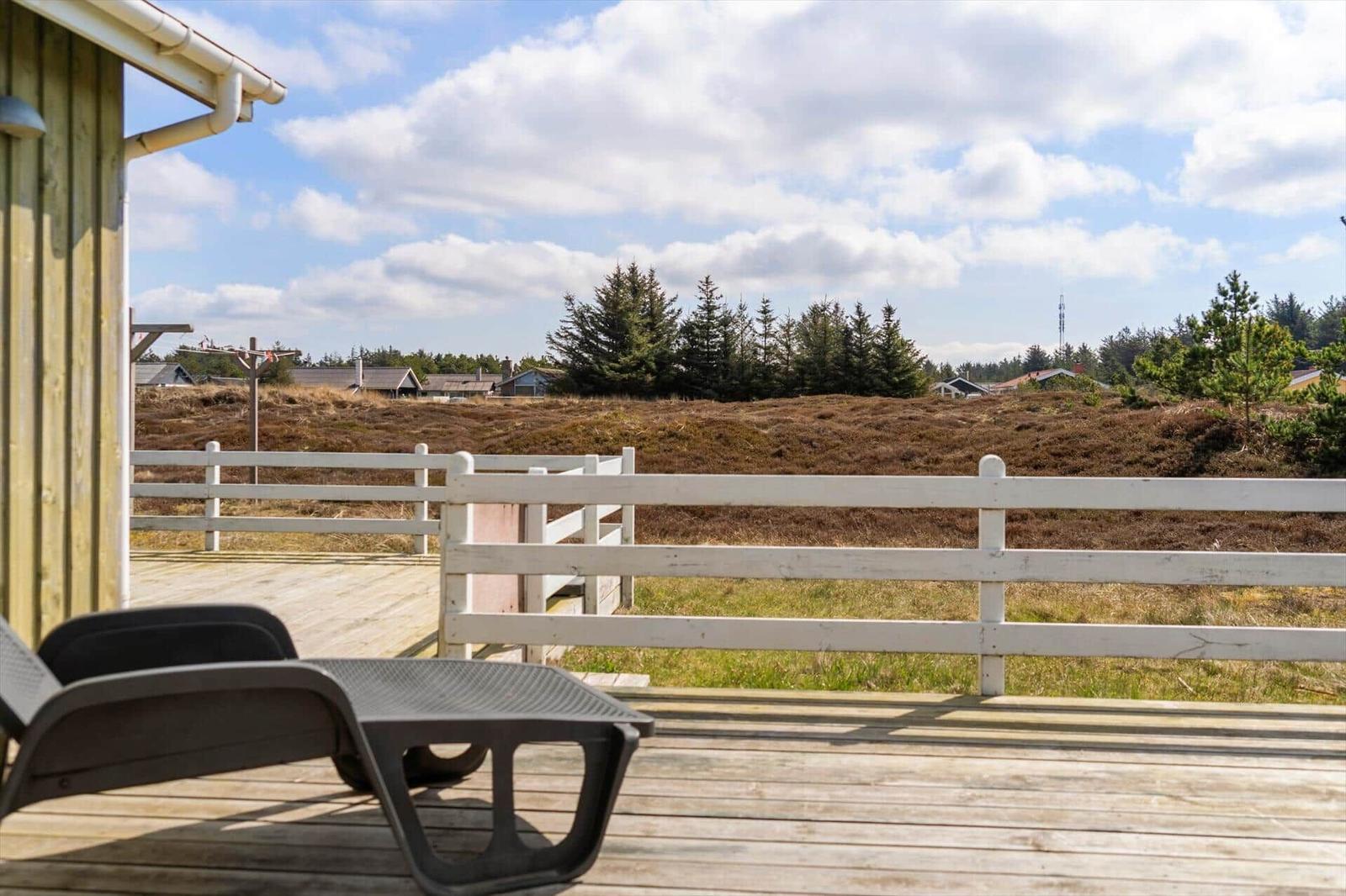 Deck with lounge chair and view of meadows and trees.