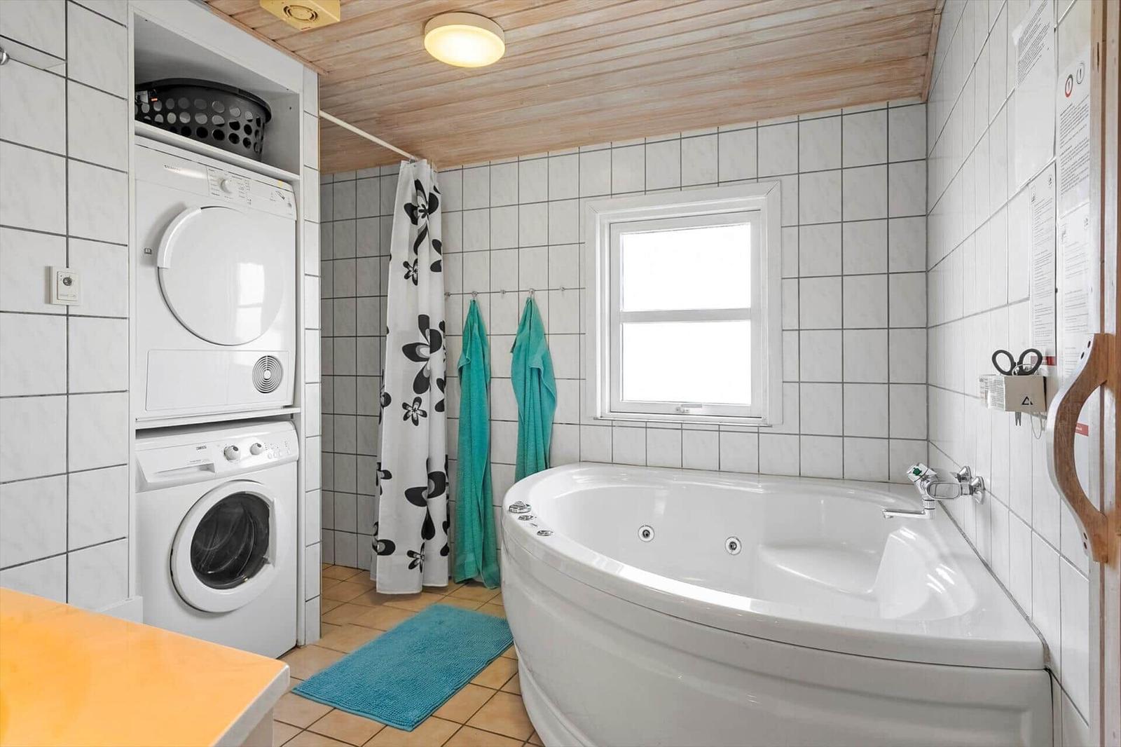 Bath with whirlpool, washing machine, and window.