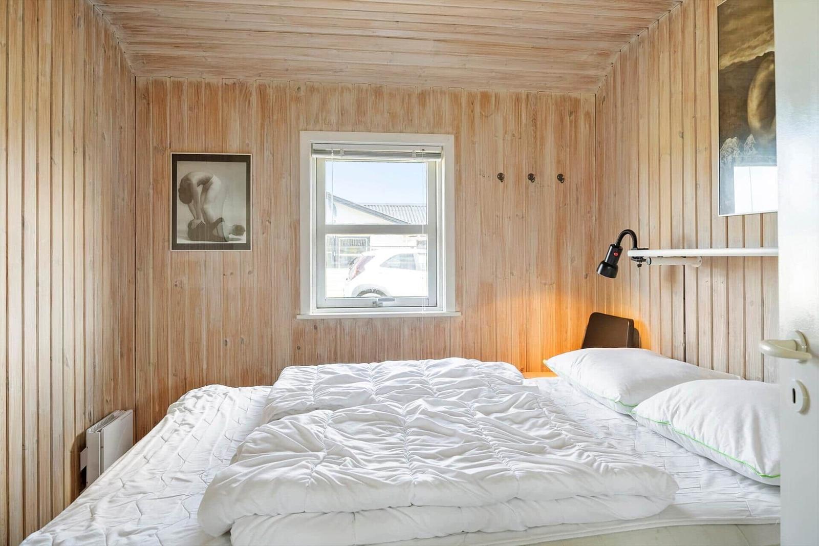 Bedroom with wooden walls, bed, and window.