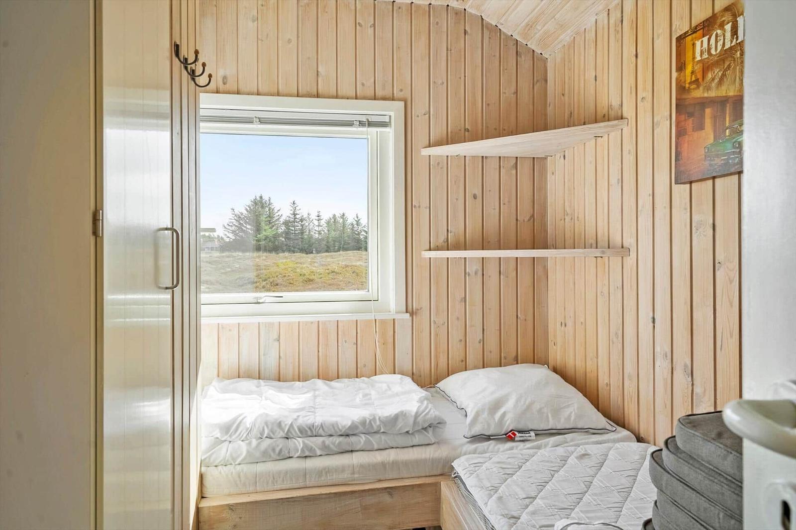 Bedroom with wooden walls, window, and mattress.
