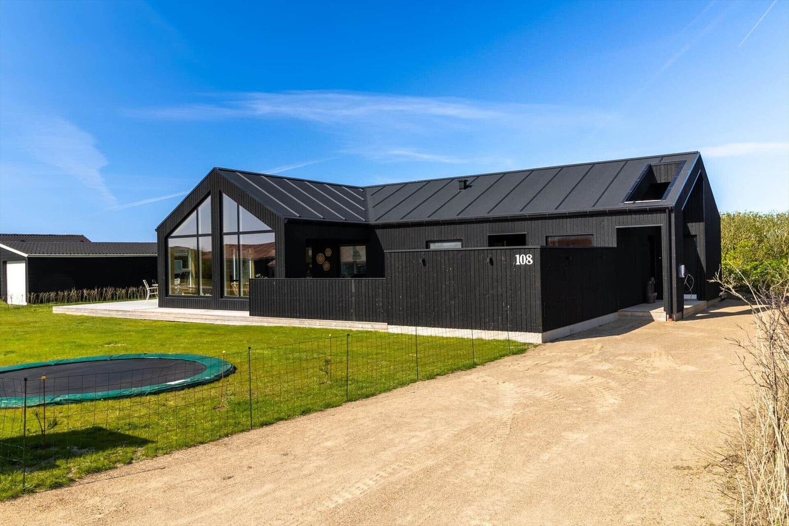 Moderne schwarze Villa mit großem Garten und Trampolin. Hausnummer 108.