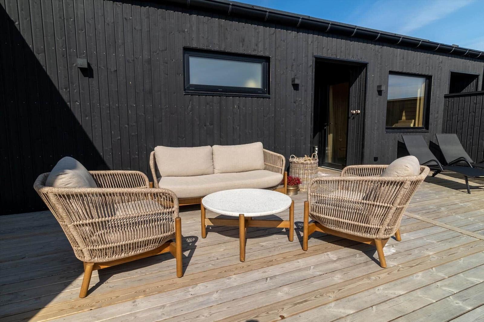 Terrasse mit Sitzgruppe und Tisch vor einem schwarzen Holzhaus
