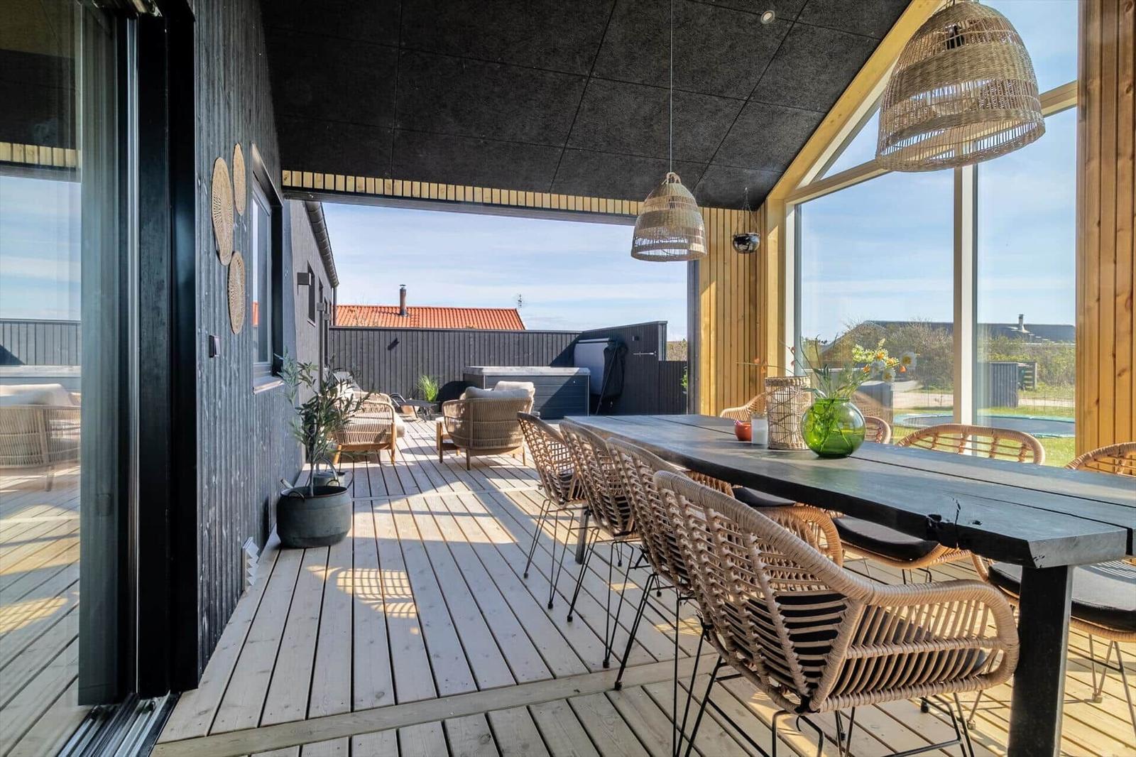 Terrasse mit Esstisch und Stühlen, Blick auf Garten und Pool.