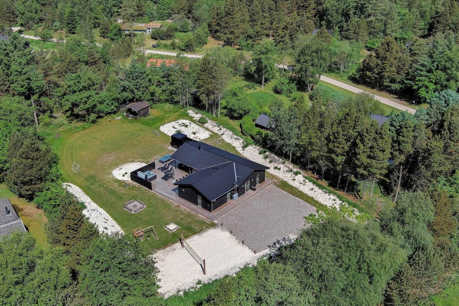 Moderne Villa mit Garten, Pool und Spielplatz in grüner Umgebung.