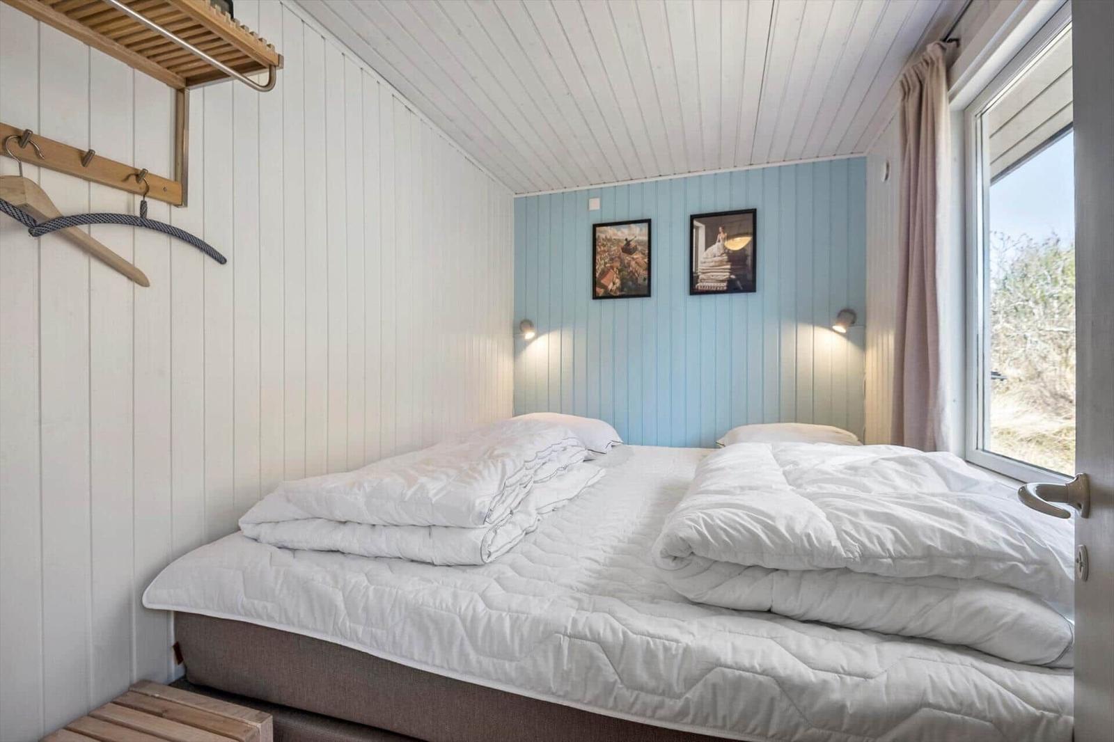 Schlafzimmer mit Bett, Fenster und Wandbildern
