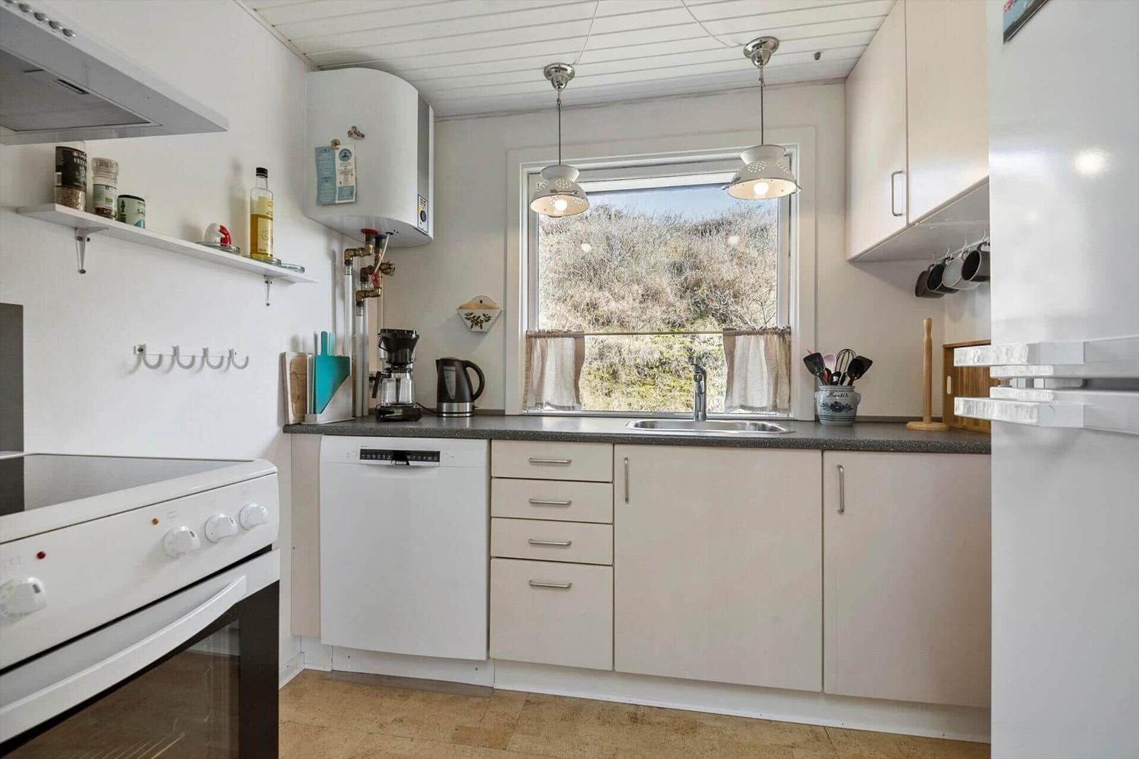 Küche mit Fenster, Spüle, Kühlschrank und Kochgeräten.