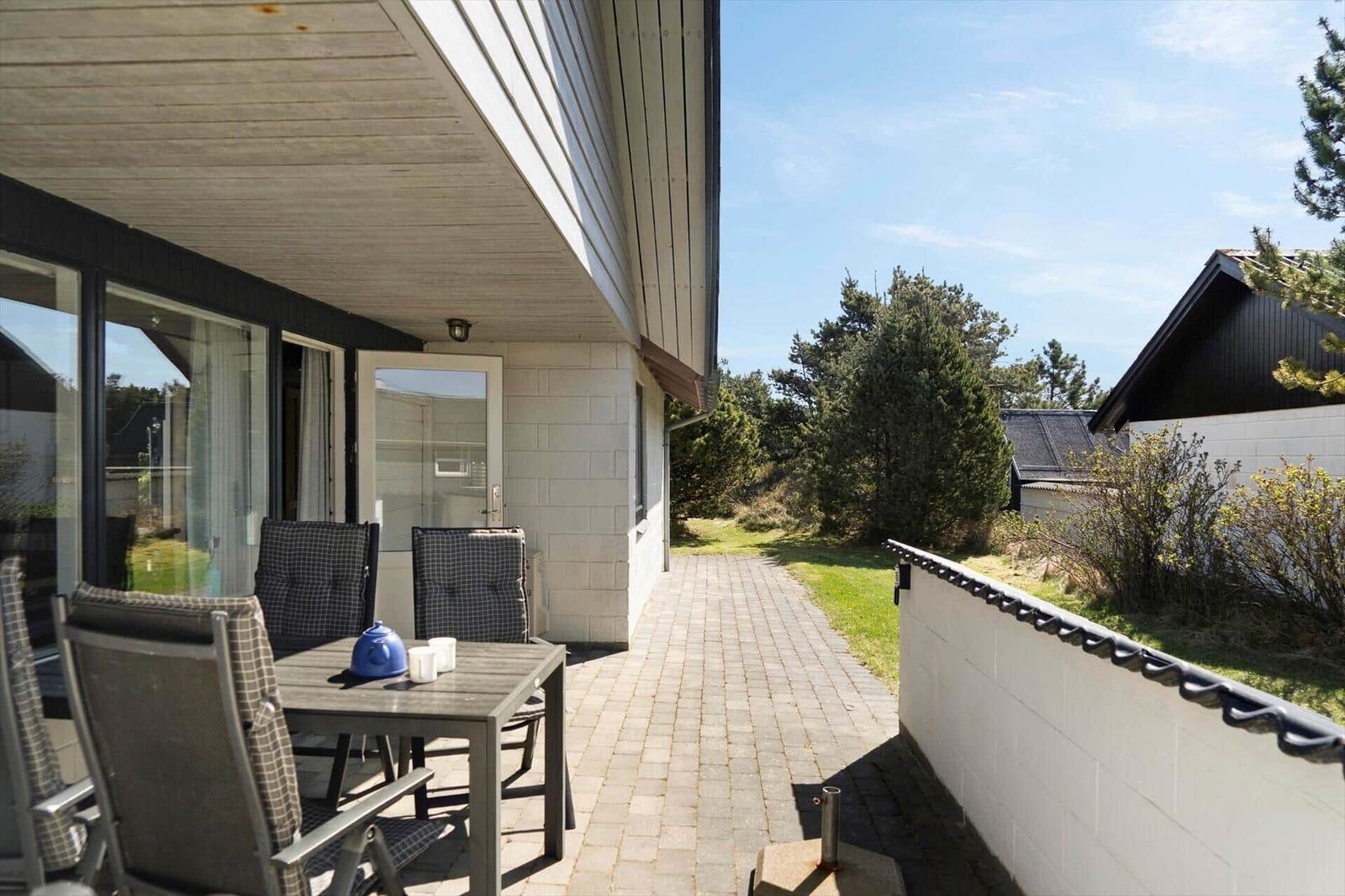 Terrasse mit Tisch, Stühlen und Blick auf Grünfläche und Nachbarhaus.