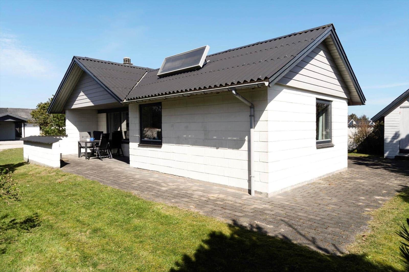 Moderne Villa mit Terrasse und Solaranlage. Grünfläche und gepflasterter Hof.
