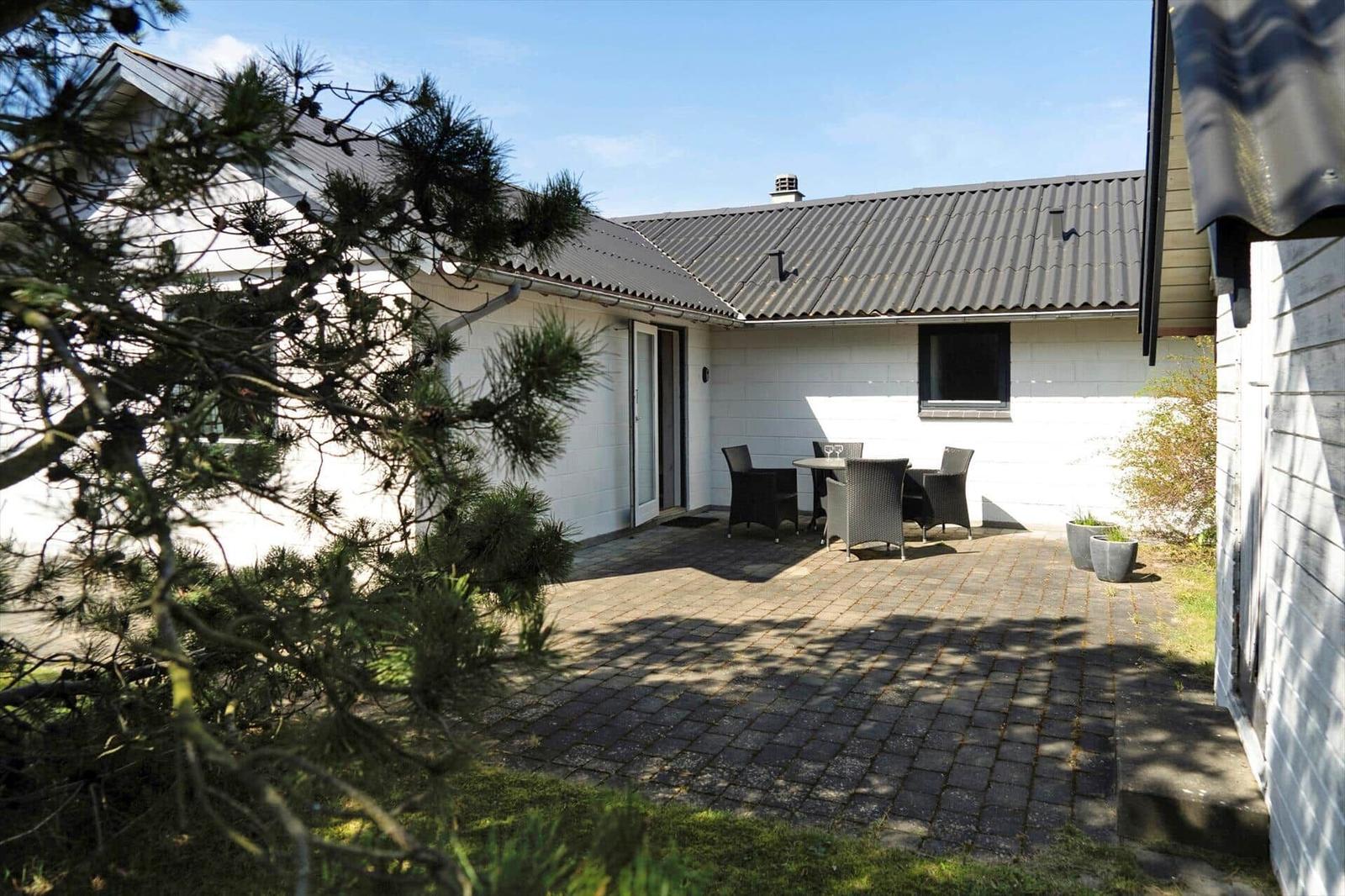 Haus mit Terrasse, Garten und Sitzgruppe unter freiem Himmel.