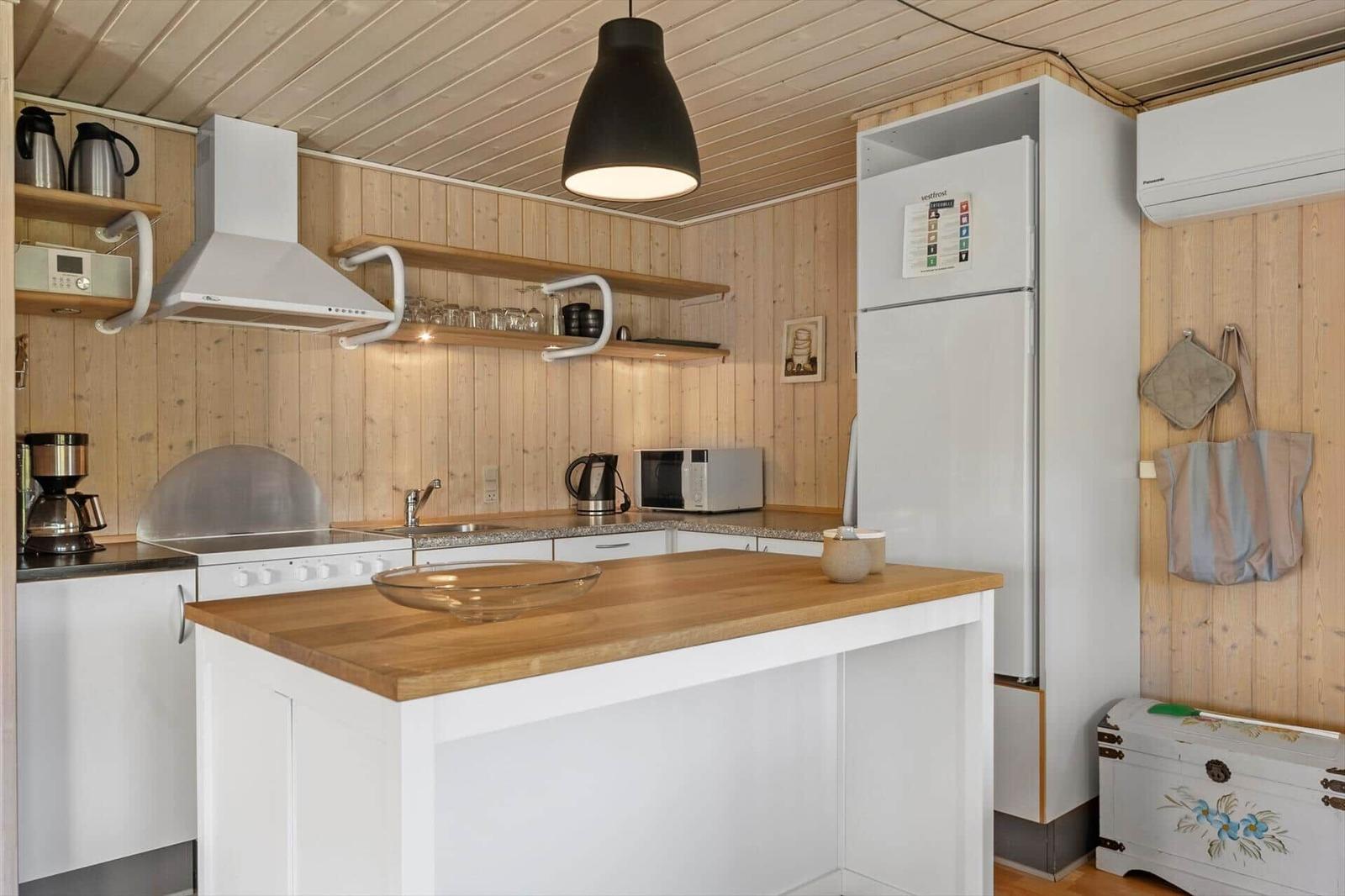 Kitchen with wooden walls, white cabinets, and kitchen island with wooden top.