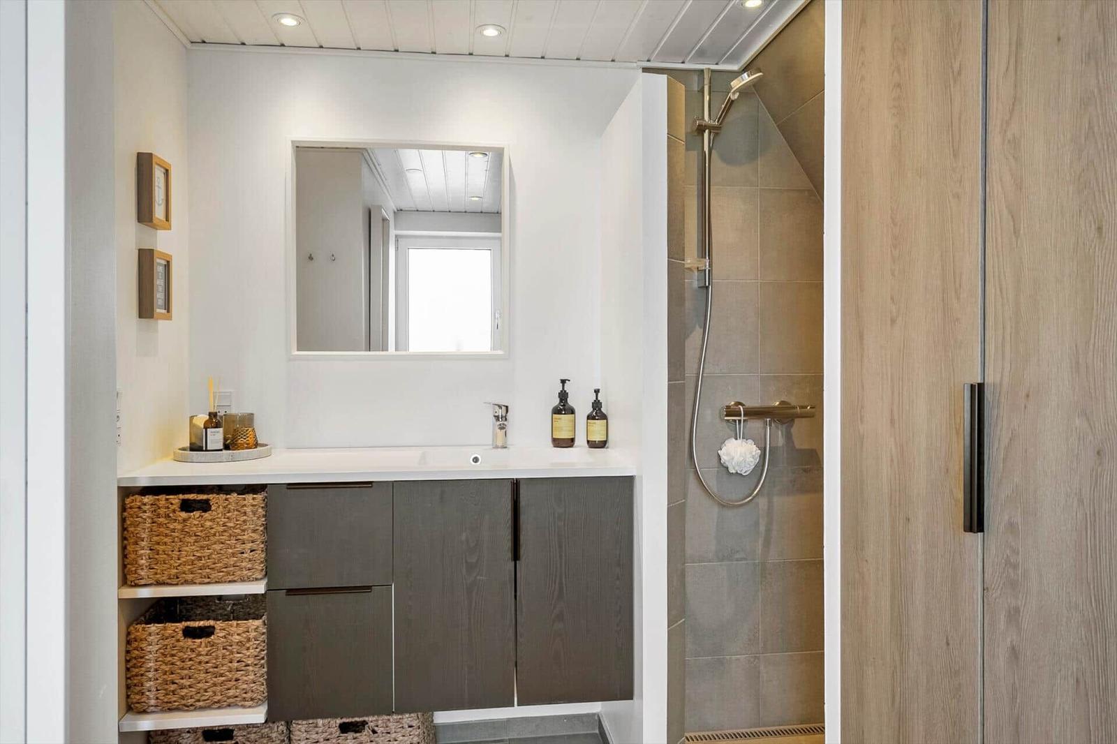 Badezimmer mit Dusche, Waschbecken und Spiegel. Holz- und Steinoptik.
