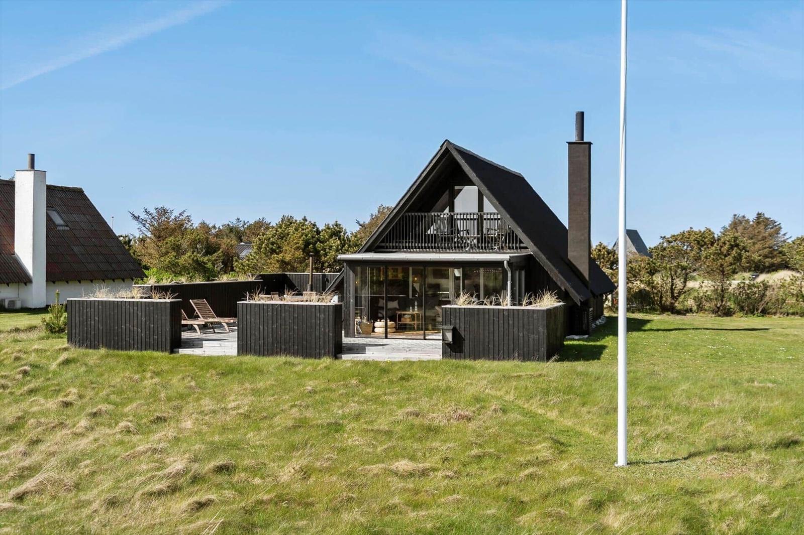 Moderne Holzhütte mit Balkon und großem Glasbereich im Grünen.